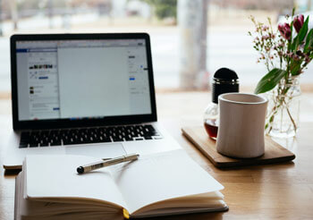 Ein Buch, eine Tasse und ein Laptop.